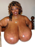Ebony woman shows off her oiled shockingly huge breasts and plays with dildo