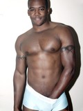 Smiling strong black guy shows off his sexy muscles and hesitates to flash his dick