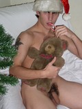 Gay boy shows his dick while posing with his teddy bear beside the Christmas tree