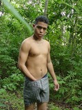 Teen boy is taking the T-shirt and shorts off in the middle of the forest