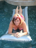 Playful juicy girl takes off her rosy bikini in the middle of the pool