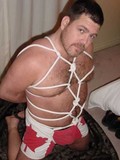 Muscular bear man is blindfolded and gagged with his body squeezed by tight rope