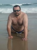 Fat hairy chested man in shades strips nude on the wild beach after swimming