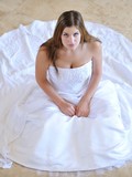 Cute faced bride posing in snow white wedding dress all over the house