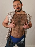 Bearded gay bear Gabe Harris strips nude to show his hairy chest, back and cock